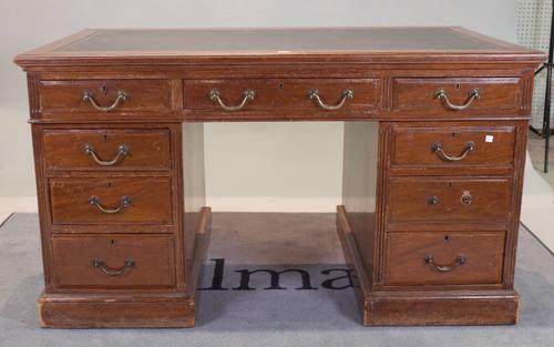 An early 20th century walnut pedestal desk, with nine drawers about the knee and gilt tooled green leather top, 138cm wide.