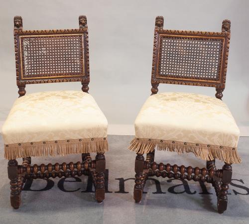 A set of six Charles II style carved oak dining chairs, with cane back panels, upholstered stuff-over-seats, on bobbin turned and square section...