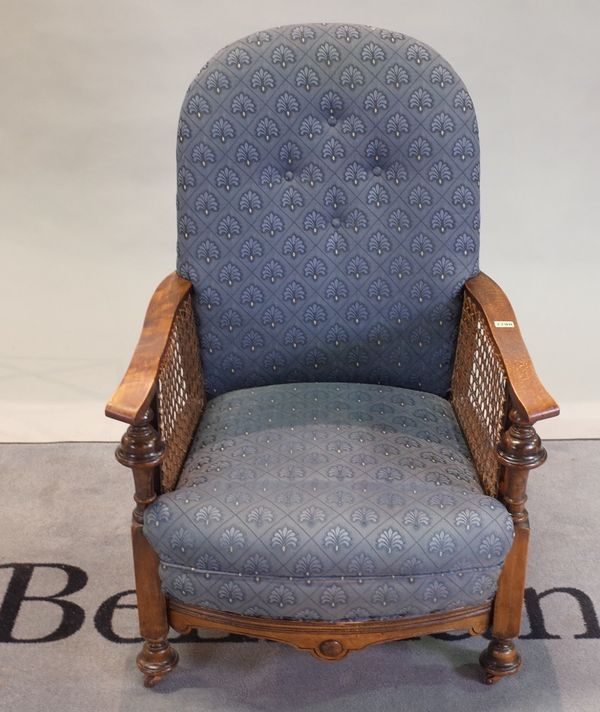 A late 19th century walnut and cane low armchair with blue upholstery, 65cm x 94cm high.