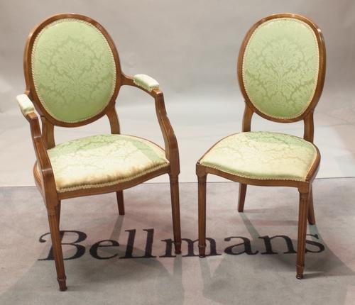 A set of nine Louis XVI style stained beech oval back dining chairs on fluted tapering supports, to include two carvers, 54cm wide x 99cm high, (9).