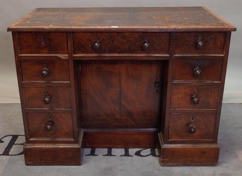 A George III mahogany kneehole writing desk with nine drawers about the knee on a plinth base, 105cm wide x 76cm high.