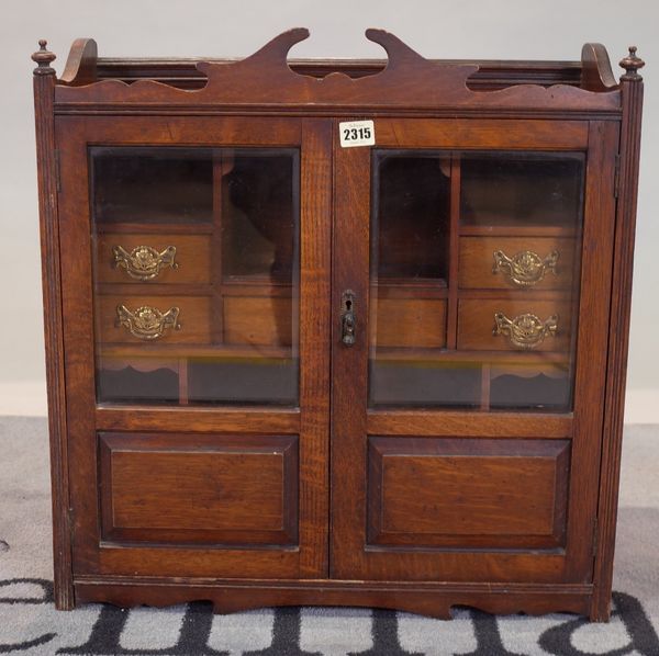 An Edwardian oak hanging wall cupboard with a central drawer flanked by two short drawers, 56cm wide x 57cm high.