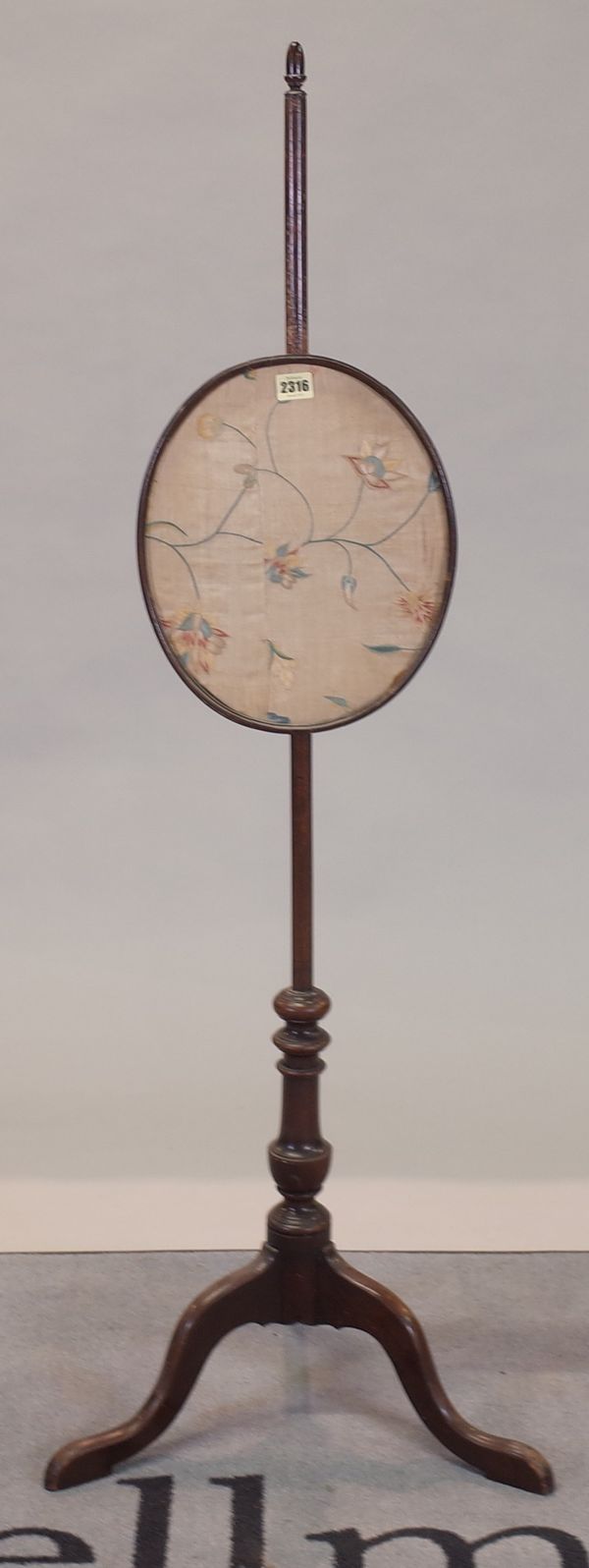 A late Victorian mahogany pole screen with oval framed silkwork on three outswept supports, 125cm high.