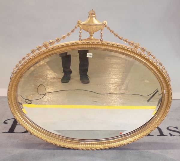 An Adams style giltwood oval wall mirror with urn and ribbon crest with bevelled glass, 98cm wide x 87cm high.
