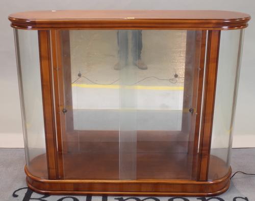 A modern fruitwood display cabinet with glass front and rounded ends, on plinth base, 120cm wide x 96cm high.