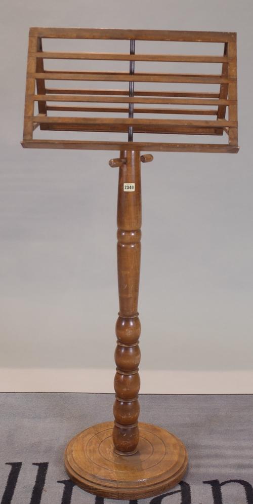An early 20th century walnut duet music stand, with turned column base, 55cm wide x 134cm high.
