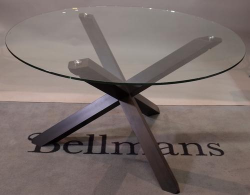 A glass circular dining table, on a stained beech 'X' frame base, 130cm diameter x 77cm high.