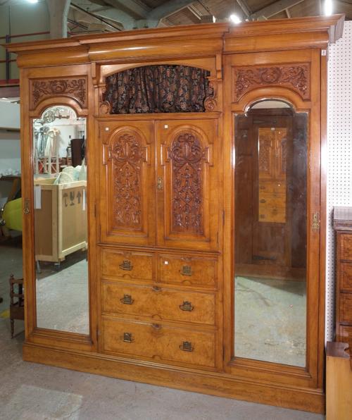 An Edwardian oak and walnut triple wardrobe with a central mirrored door over a three drawer base, 220cm wide x 240cm high.