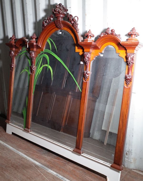 A large Victorian mahogany triple plate overmantel mirror, circa 1880, with moulded arched cornice surmounted by carved fruits and turnings, the...