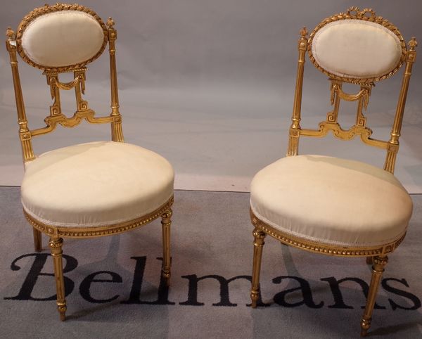 A pair of gilt framed side chairs, with oval padded backs on turned supports, 45cm wide x 81cm high, (2).