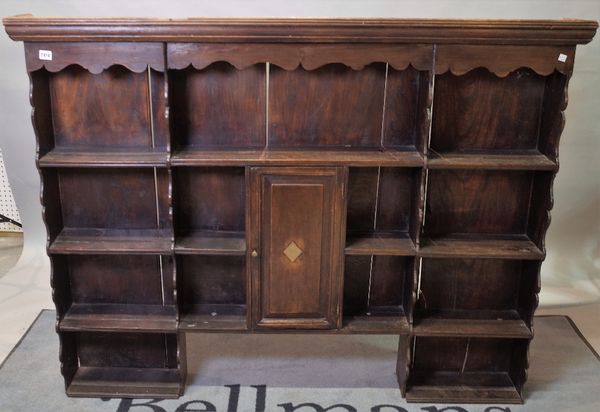 An 18th century French oak enclosed four tier plate rack, centred by cupboard, 150cm wide x 118cm high.