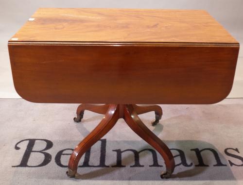 A George III mahogany ebony strung supper table, with hinged drop leaves and end drawer, ring turned pillar and quadripartite base, 91.5cm wide x...