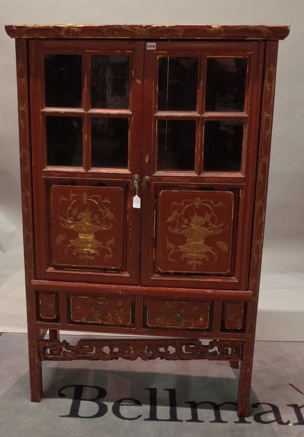 A Chinese carved red lacquered and gilt decorated cabinet, 19th century, enclosed by a pair of glazed and raised and fielded panel doors with two...