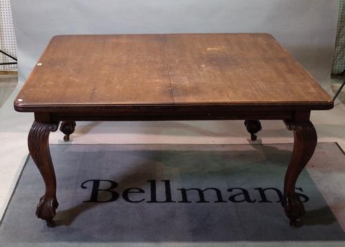 An early 20th century walnut extending dining table, with two extra leaves, on leaf carved cabriole legs, claw and ball feet, 121cm wide x 145cm long...