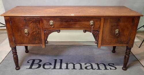 A George III mahogany sideboard, the centre drawer above scroll and fan carved brackets, flanked by cupboards, on turned legs, 155cm wide x 79cm...