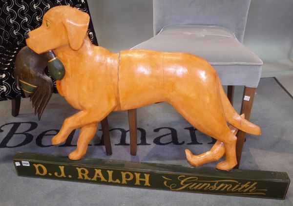 'D. J. Ralph Gunsmith', a modern painted pine advertising sign, formed as a dog with a duck, 106cm wide x 67cm high, (a.f.).