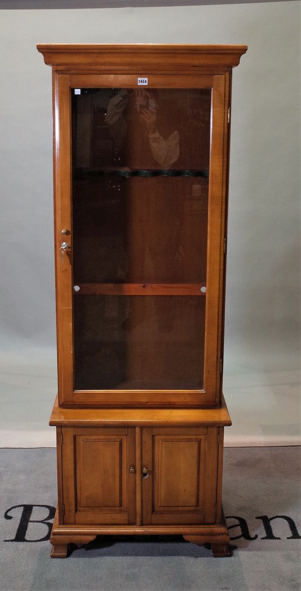 A modern stained beech gun display cabinet, with cupboard base, on bracket feet, 63cm wide x 180cm high.