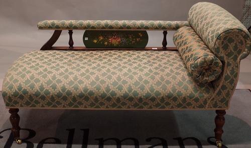 A Victorian style stained beech framed chaise longue, with foliate painted back on turned supports, 117cm wide x 70cm high.