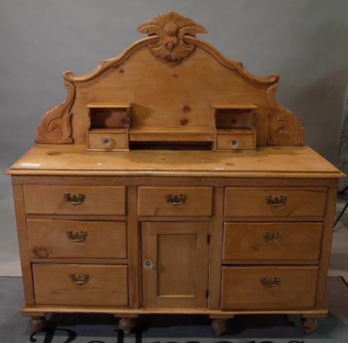 An early 20th century pine dresser base with nine drawers over a cupboard base, on turned supports, 142cm wide x 145cm high.
