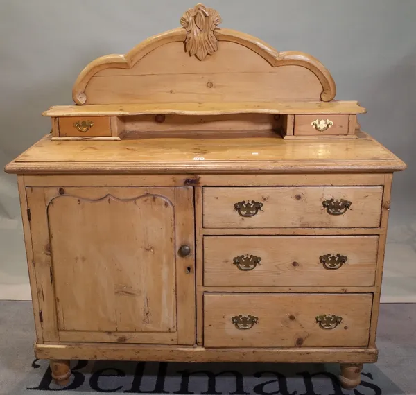An early 20th century pine side chest with a cupboard door flanked by three short drawers on turned supports, 120cm wide x 130cm high.