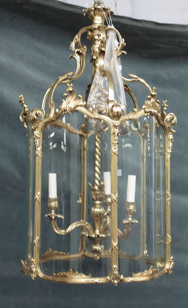 A gilt brass hexagonal hall lantern, in the Louis XV style, 20th century, with serpentine glazed panels and internal three light pendant, (one glass...