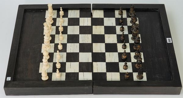 A French bone 'Regence' pattern chess set, nine ivory and nine ebony gaming counters and a folding ebony and bone inlaid chess and backgammon board,...