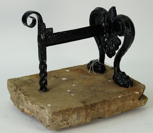 A black painted cast iron boot scraper on paw feet mounted on a rectangular stone slab, 32cm high x 36cm wide.