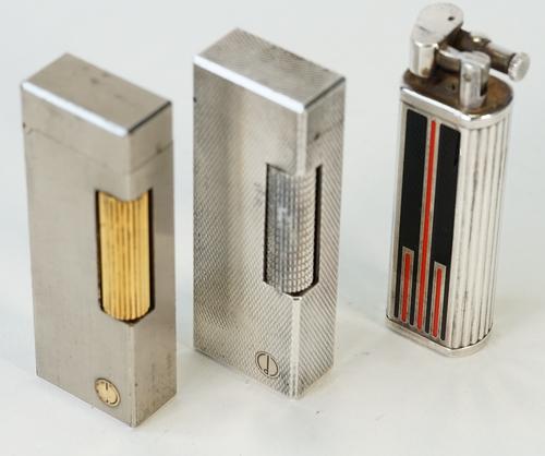 Three Dunhill lighters, one having a black and red lacquer design and numbered to the base 42661, (3).