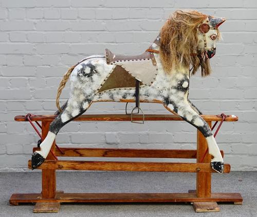 A wooden dapple grey painted rocking horse, early 20th century, on a stained pine base, length 130cm, height 110cm.