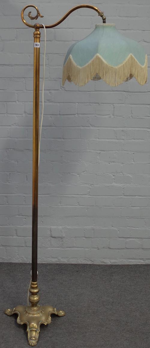 An early 20th century brass standard lamp, raised on a triform base with paw feet, with shade, 168cm high