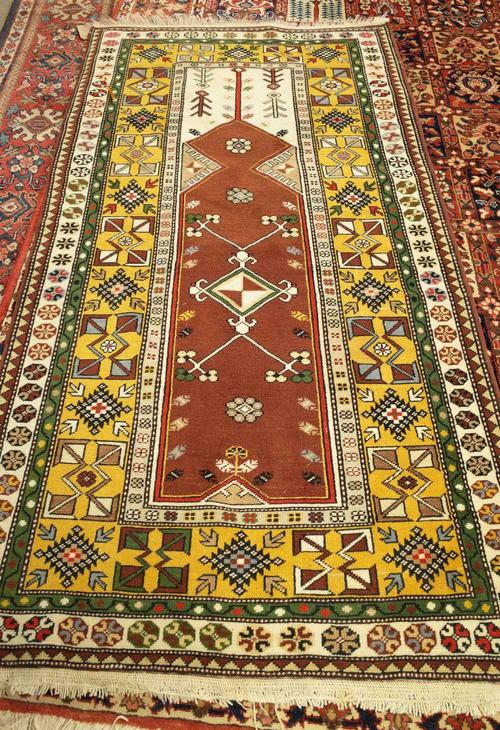 A Turkish prayer rug, the brown mehrab with a diamond to centre, ivory arch; a saffron diamond and arrow motif border, 210cm x 110cm.