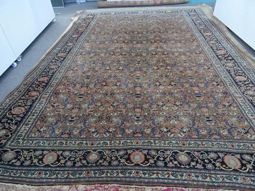 A Khorassan carpet, Persian, the madder field with an allover floral vine design; a dark indigo border of palmettes and floral vines, 532cm x 362cm.