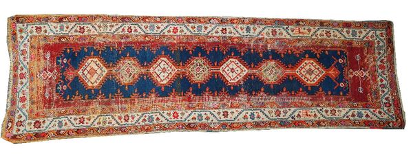 A Turkish runner, the indigo field with seven medallions, an ivory waved vine border, 363cm x 110cm, dated 1333.