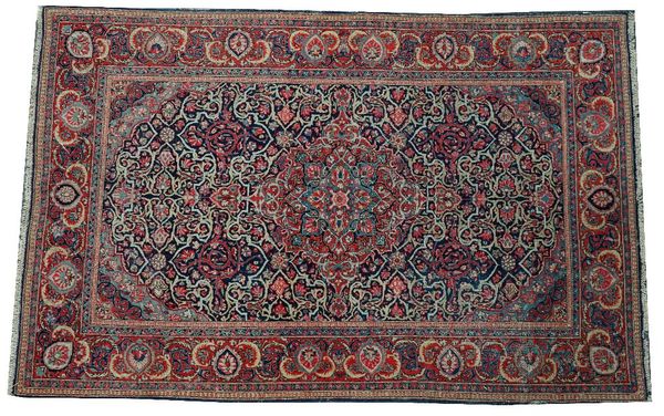 A Kashan rug, Persian, the indigo field with a madder and pale indigo medallion, matching spandrels, all with angular floral vines; a madder...