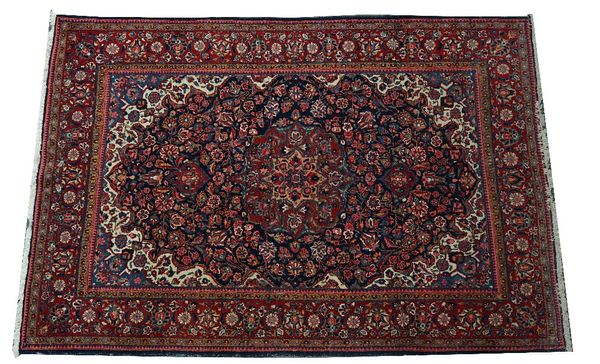 A Kashan rug, Persian, the indigo field with a madder and pink medallion, ivory and indigo spandrels, all with intricate floral sprays; a madder...