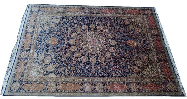 A Tabriz carpet, Persian, the dark indigo field with a large faceted central medallion, matching spandrels, all with intricate floral vines, a...