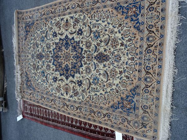 An Isfahan part silk rug, Persian, the ivory field with an indigo faceted medallion, matching spandrels all with floral sprays, a beige palmette and...