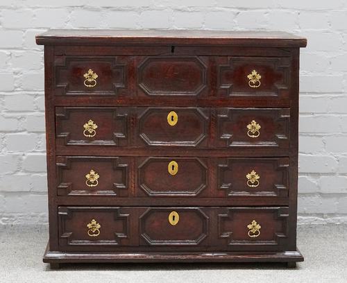 A Queen Anne oak chest, the lift top revealing a candle box and short drawer fitted interior, the geometric moulded front with single dummy over...