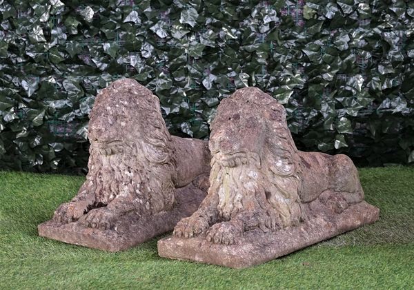 A pair of reconstituted stone figures of recumbent lions on rectangular bases, 77cm wide x 46cm high.