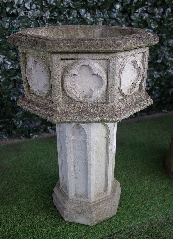 A reconstituted stone Gothic revival octagonal planter/font with relief quatrefoil panels, 50cm wide 80cm high.