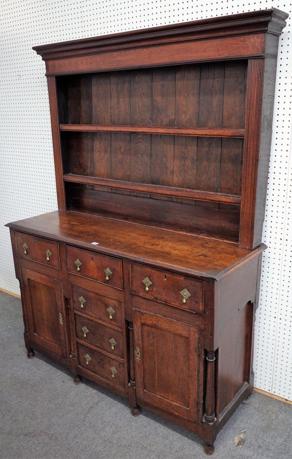 A George III oak dresser, the enclosed two tier plate rack, over six drawers and pair of cupboards, flanked by turned supports, 140cm wide x 185cm...