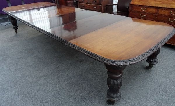 A Victorian mahogany double end extending dining table, with leaf carved border and reeded baluster supports, six extra leaves contained in a hutch...