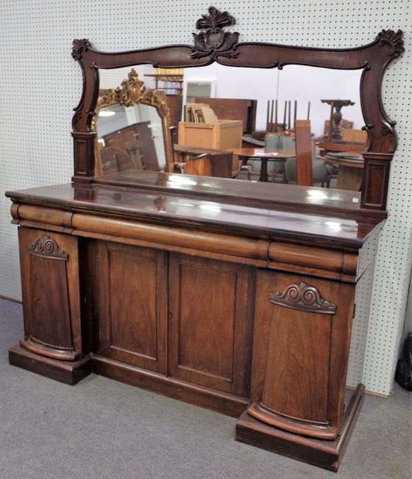 An early Victorian rosewood sideboard, with a foliate and scroll carved mirror back, three frieze drawers above an inverted breakfront fitted with...