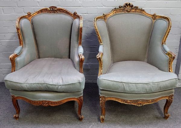 A pair of Louis XV style gilt framed tub back armchairs, with serpentine seats, on scroll supports, 72cm wide x 100cm high, (2).