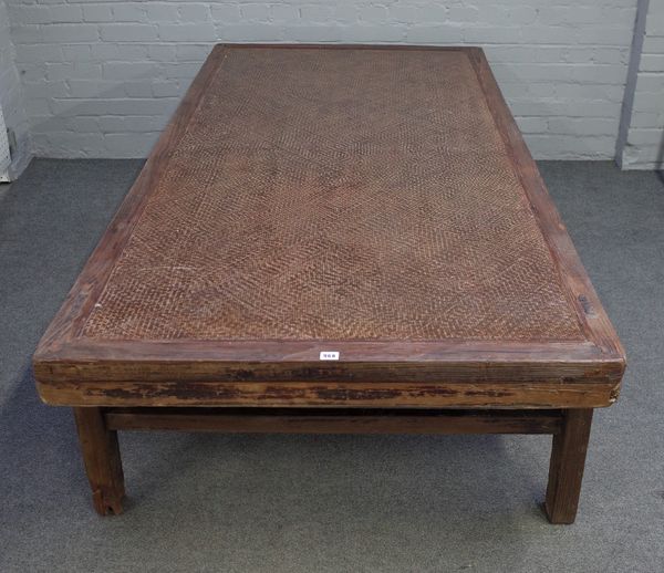 A 19th century Chinese elm framed opium bed, with rattan inset, on block supports, 104cm wide x 210cm long.