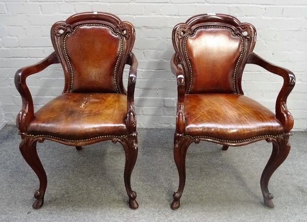 A pair of Victorian mahogany framed brown leather upholstered open armchairs, with serpentine seats and scroll supports, 56cm wide x 94cm high.