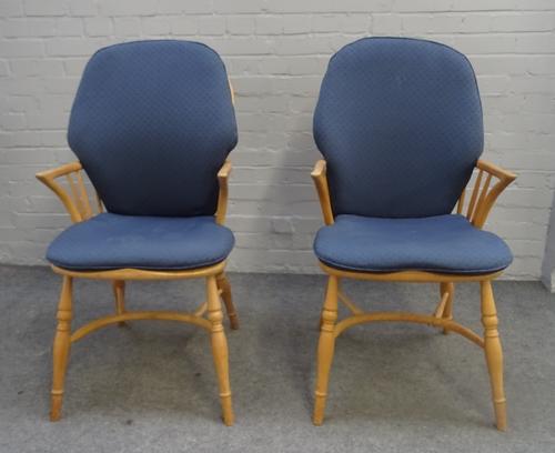 Ercol; a pair of ash and elm stick back Windsor chairs, on turned supports, united by crinoline stretcher, 55cm wide x 106cm high, (2).