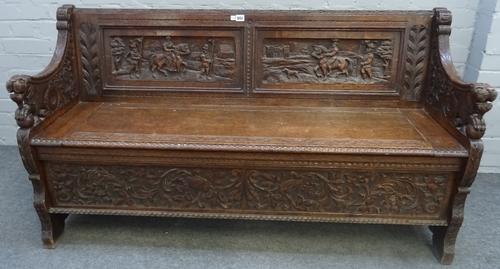 Edwards and Roberts; a carved oak box seat settle, with beast arm finials, 142cm wide x 78cm high.