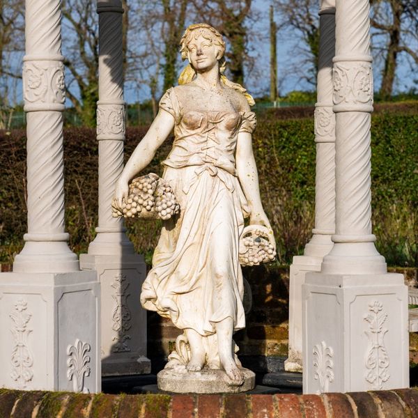 A RECONSTITUTED STONE FIGURE MODELLED AS A FEMALE GRAPE PICKER