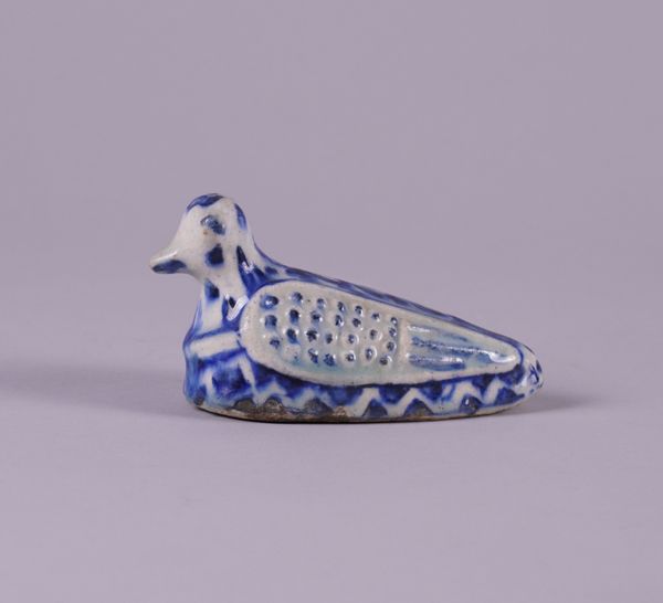 A PERSIAN POTTERY BLUE AND WHITE RATTLE IN THE FORM OF A BIRD